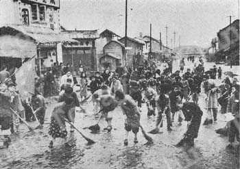 
Housewives turn out to clean a Peking street. Dirt and garbage have disappeared from public thoroughfares since householders were organized for regular clean-ups of this kind.
