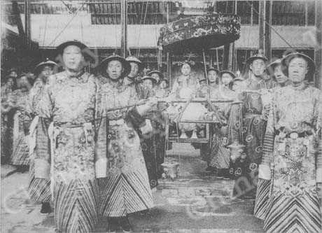 
L'impératrice douairière Cixi se déplaçait en fauteuil à porteurs dans le Palais impérial. Le chef des eunuques, Li Lianying, est le premier, à droite.
